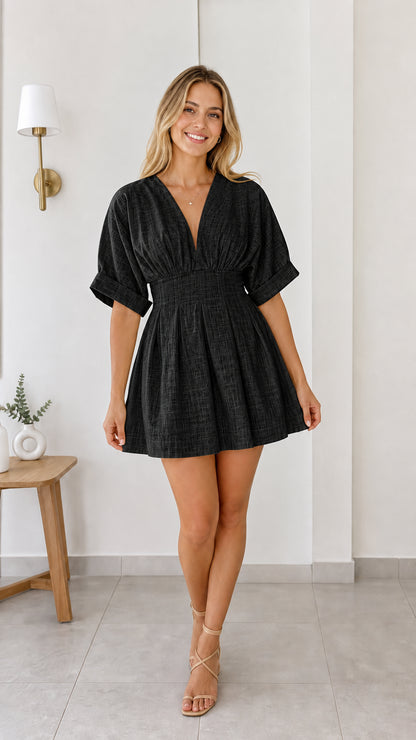 Model wearing black deep V-neck pleated waist mini dress