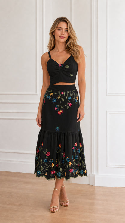 Model wearing black floral embroidered crop top and tiered midi skirt set