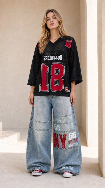 Full front view of black oversized mesh athletic jersey top paired with wide-leg jeans