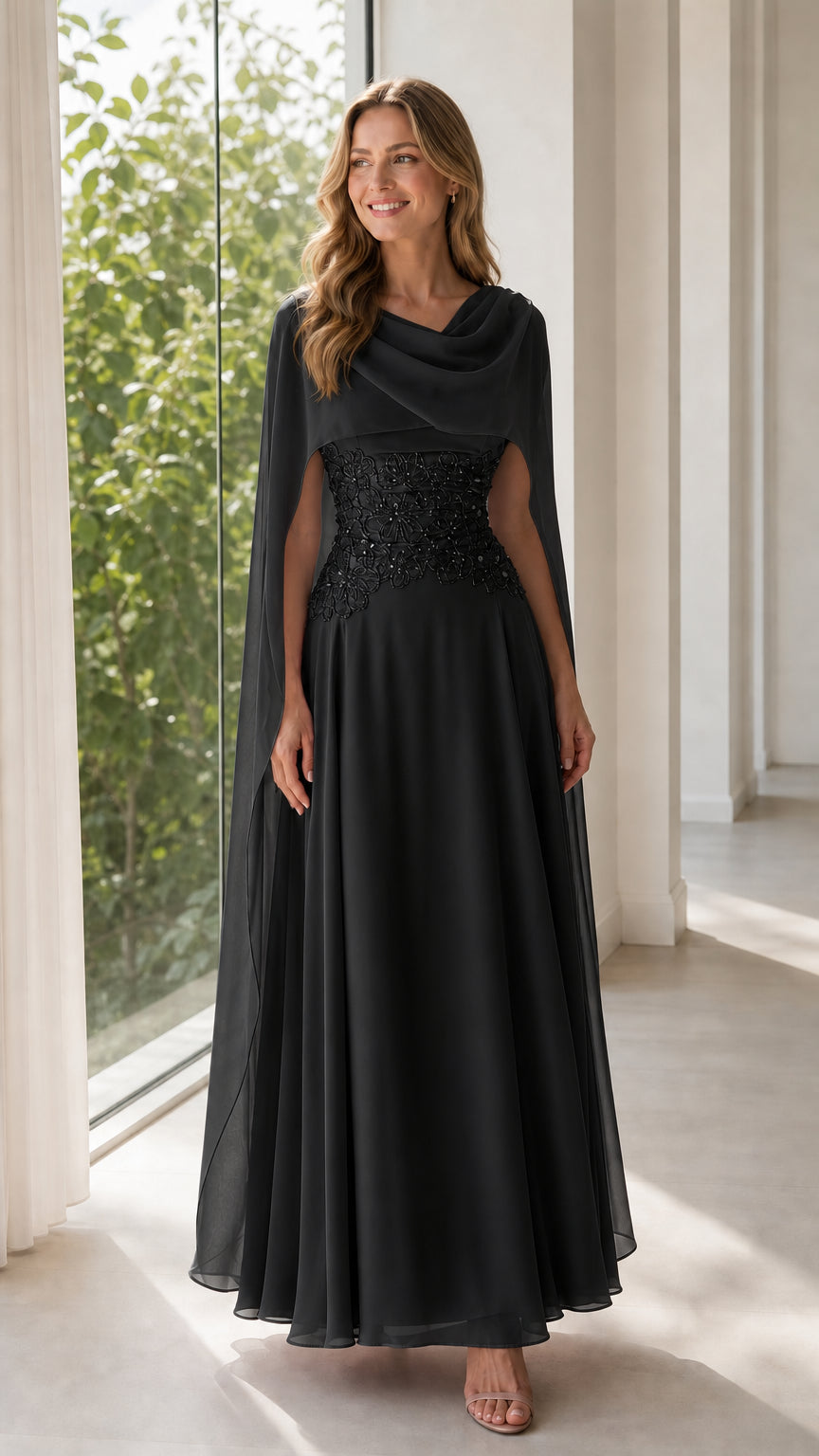 Front view of black chiffon cape evening gown with embroidered waist detail
