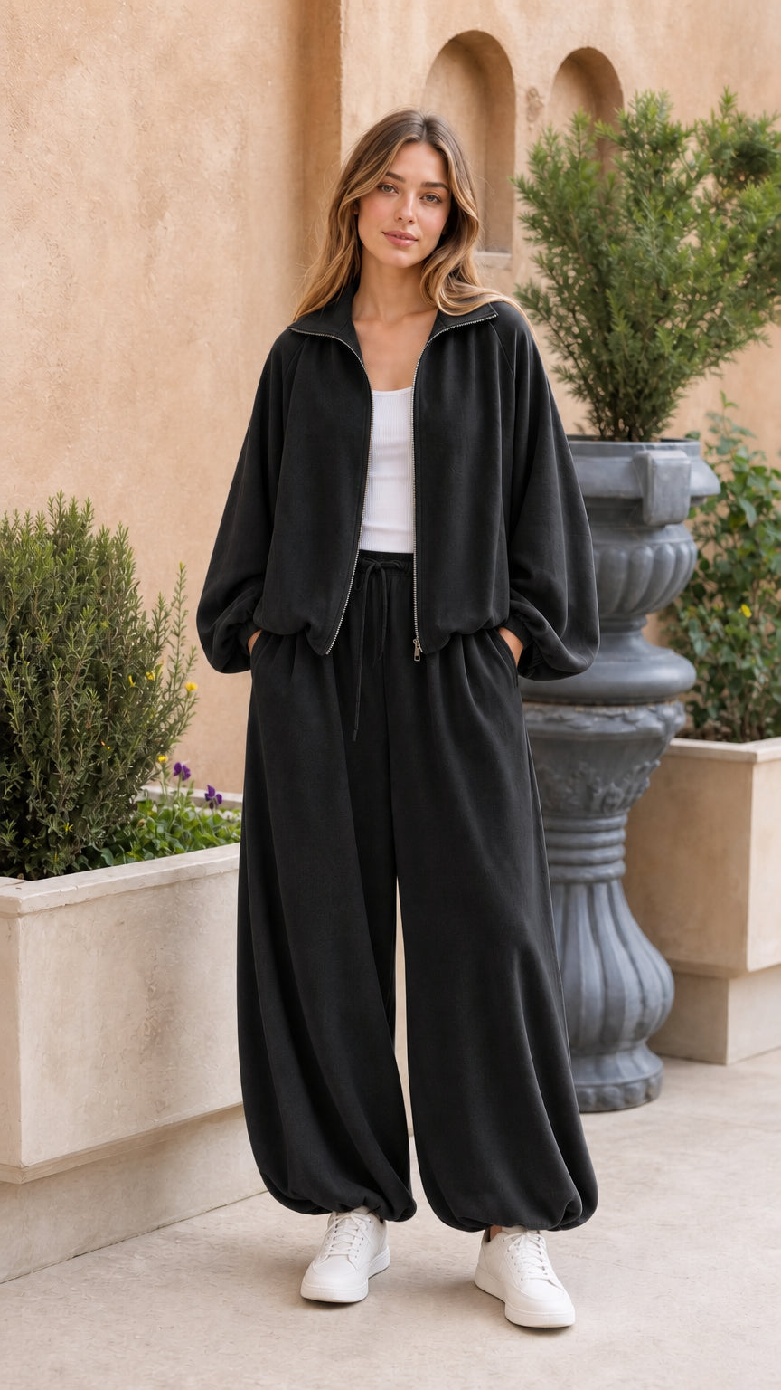 Full-body view of woman wearing black 2-piece fleece tracksuit set