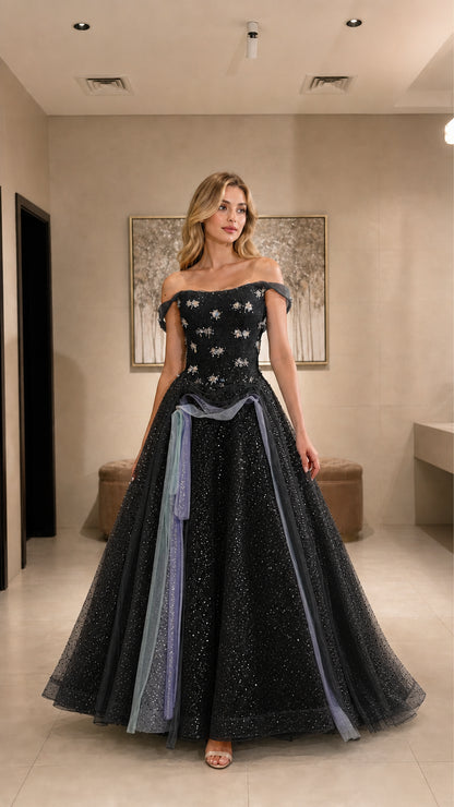 Model wearing black glitter tulle ball gown with silver floral appliqués and draped waist
