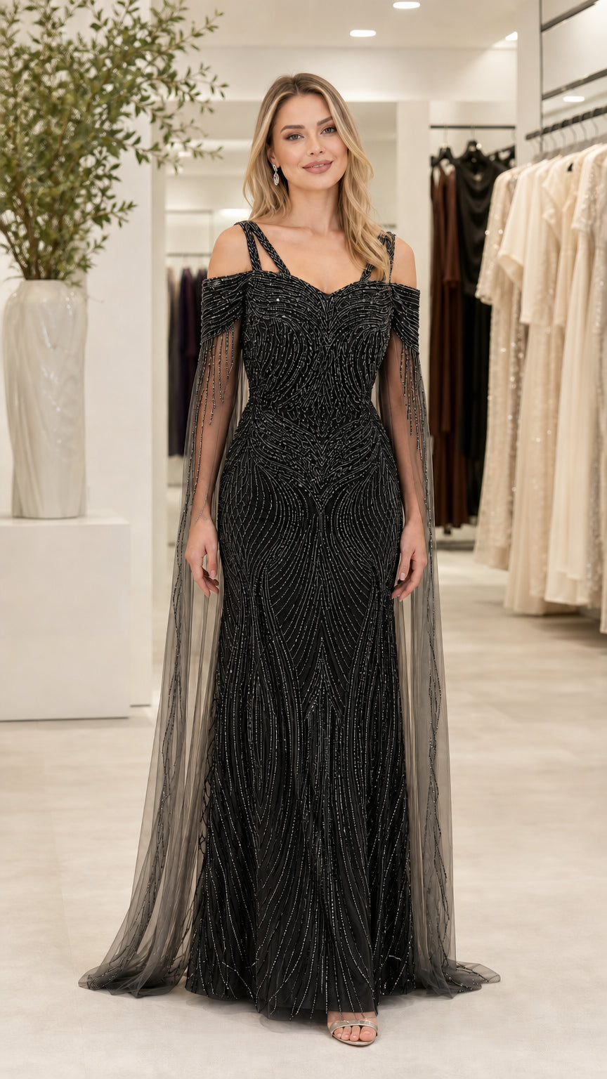 Front view of black beaded cold shoulder evening gown with sheer cape sleeves