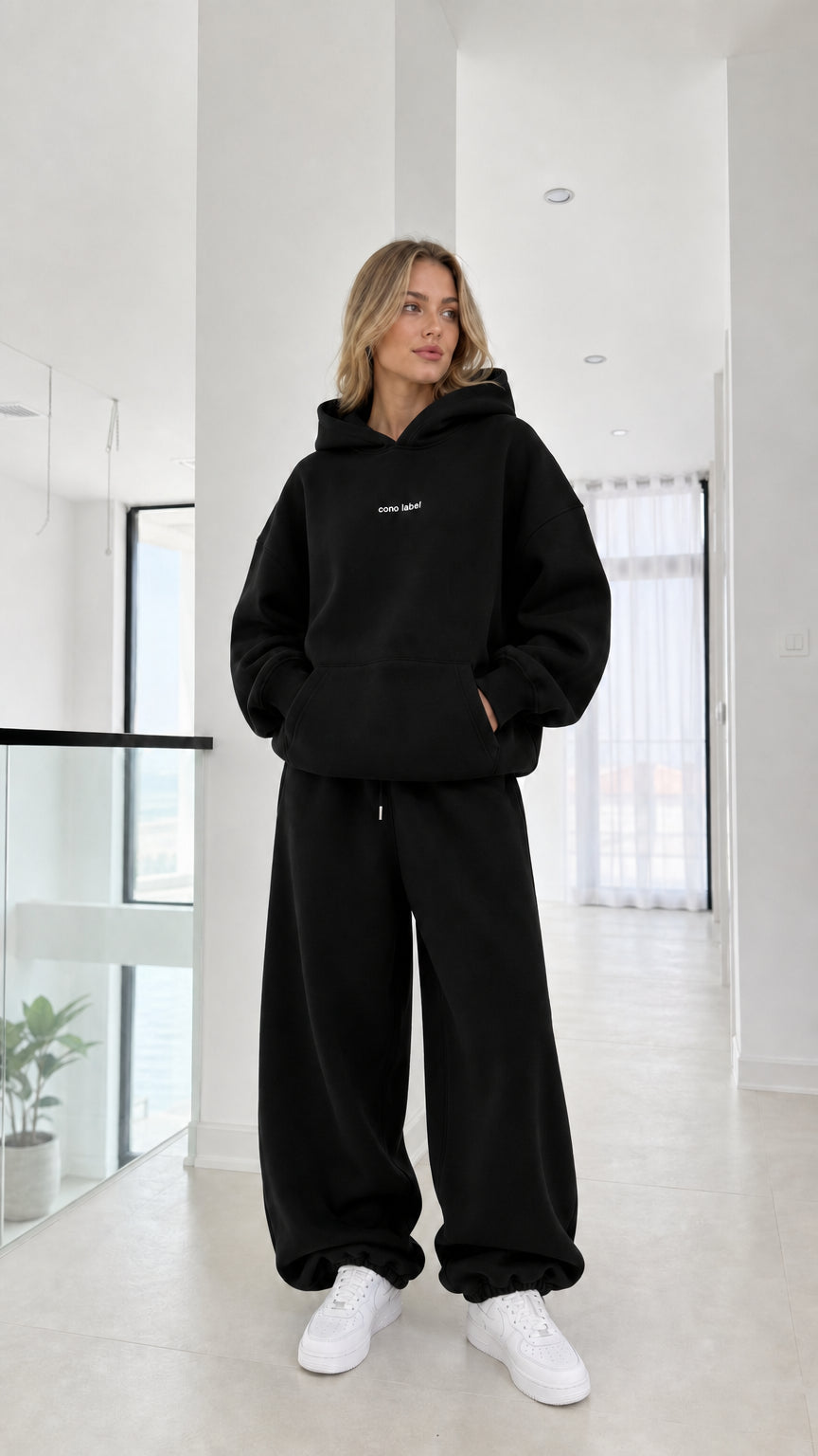 Full-length view of model wearing the black oversized hoodie and sweatpants set
