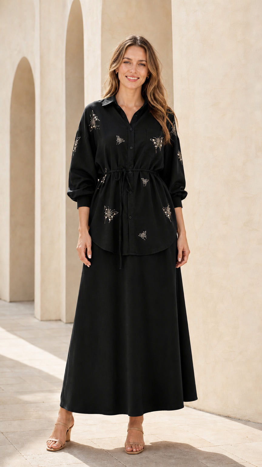 Woman wearing black embellished long sleeve button-up top and matching maxi skirt set