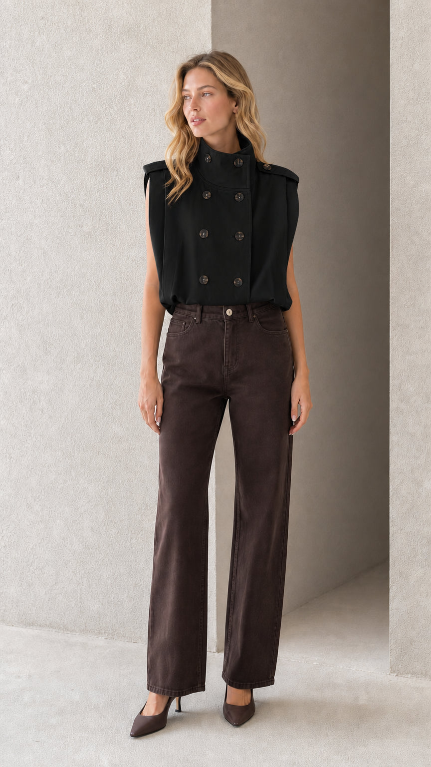 Model wearing black sleeveless double-breasted high neck blouse with dark pants