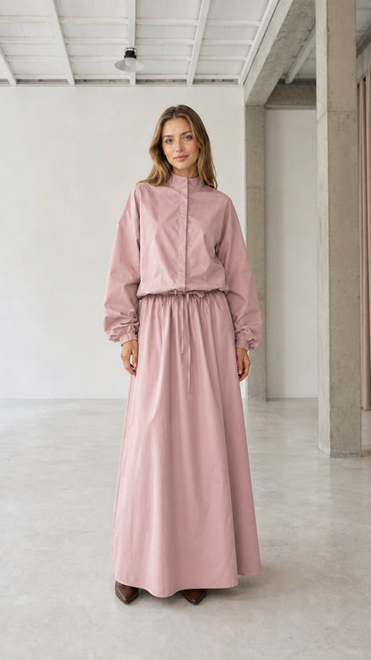 Front view of woman wearing dusty pink long sleeve stand collar drawstring maxi dress