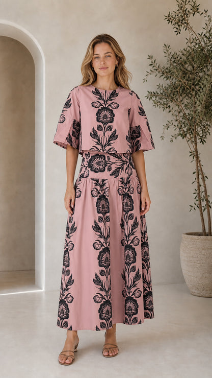 Woman wearing dusty pink floral print matching crop top and maxi skirt set