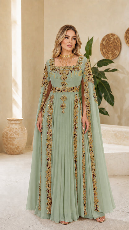 Model wearing sage green cape sleeve formal dress with golden embroidery