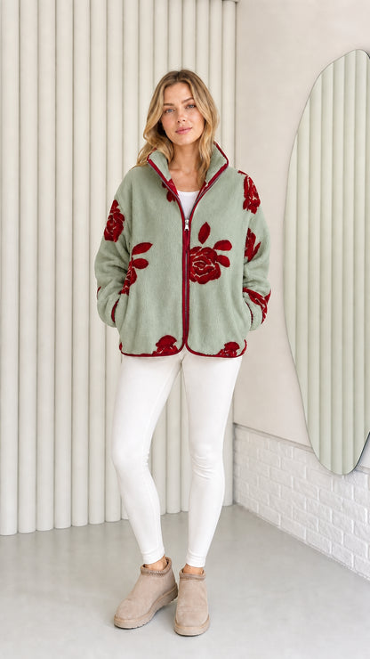 Model wearing sage green fleece jacket with red floral pattern