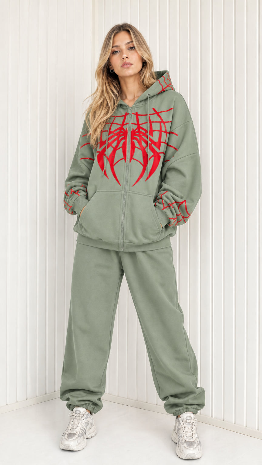 Front view of model wearing sage green graphic spider web zip hoodie and sweatpants set