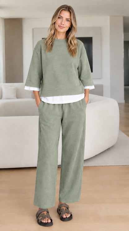 Full-body studio view of woman wearing sage green relaxed two-piece loungewear set