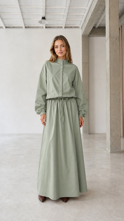 Front view of woman wearing sage green long sleeve stand collar drawstring maxi dress