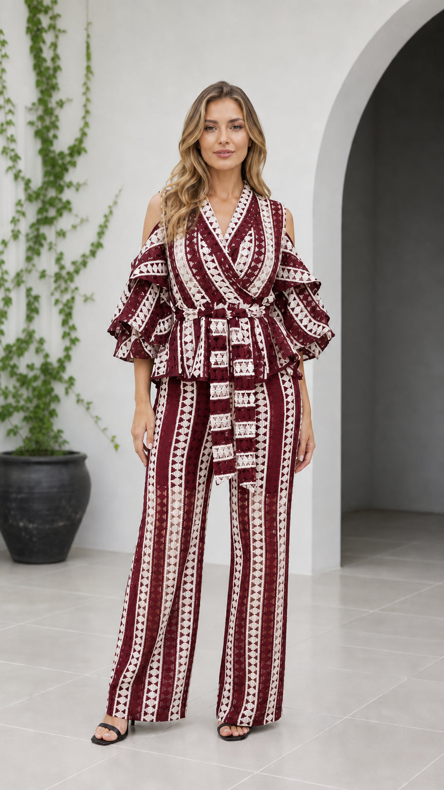 Front view of woman wearing burgundy red geometric cold shoulder wide-leg jumpsuit
