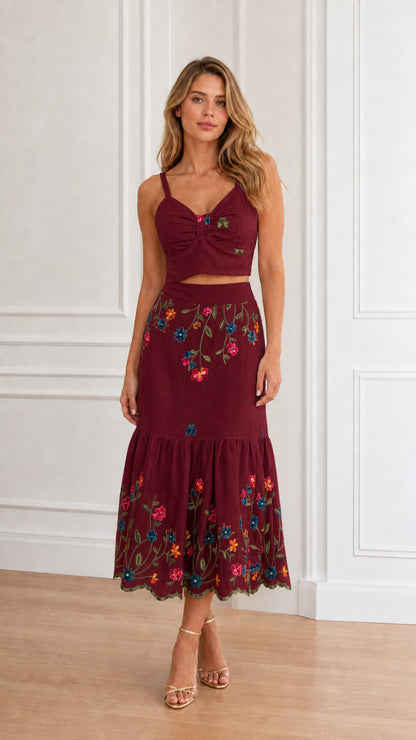 Model wearing burgundy floral embroidered crop top and tiered midi skirt set