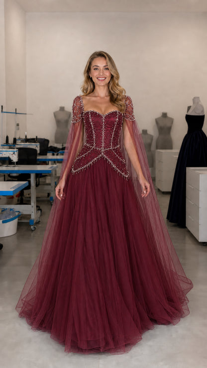 Front view of burgundy red beaded corset ball gown with sheer cape