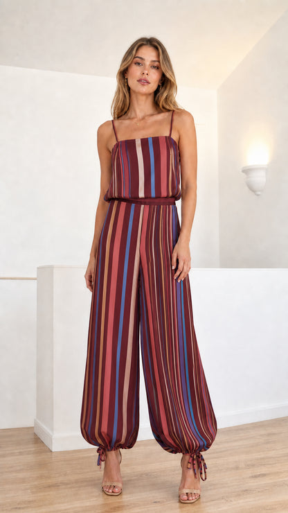 Model wearing burgundy plum multi-colored striped cami jumpsuit