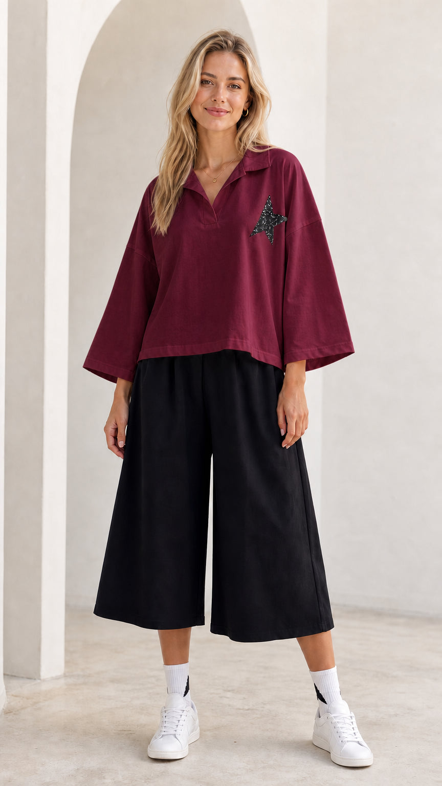 Full-length view of model wearing burgundy red star graphic polo shirt and cropped culottes