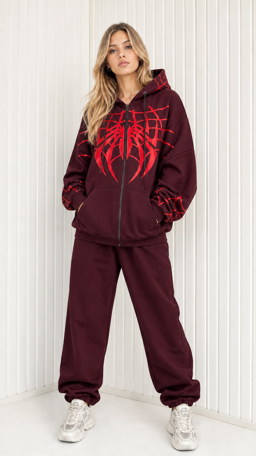 Front view of model wearing burgundy graphic spider web zip hoodie and sweatpants set