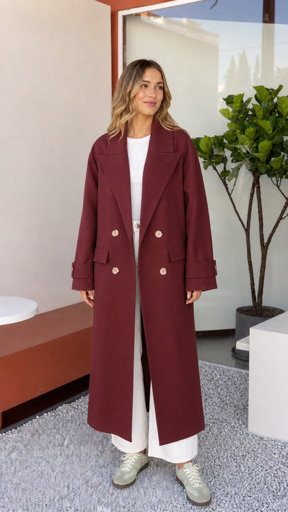 Front view of woman wearing rich Burgundy double-breasted maxi trench coat