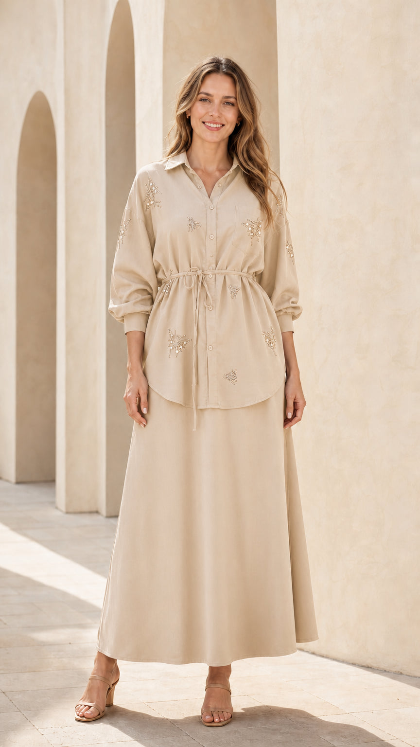 Woman wearing beige embellished button-down tunic top and maxi skirt set