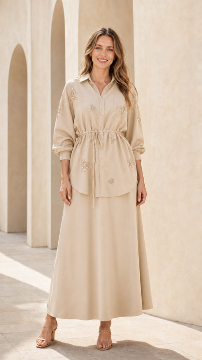 Woman wearing beige embellished button-down tunic top and maxi skirt set