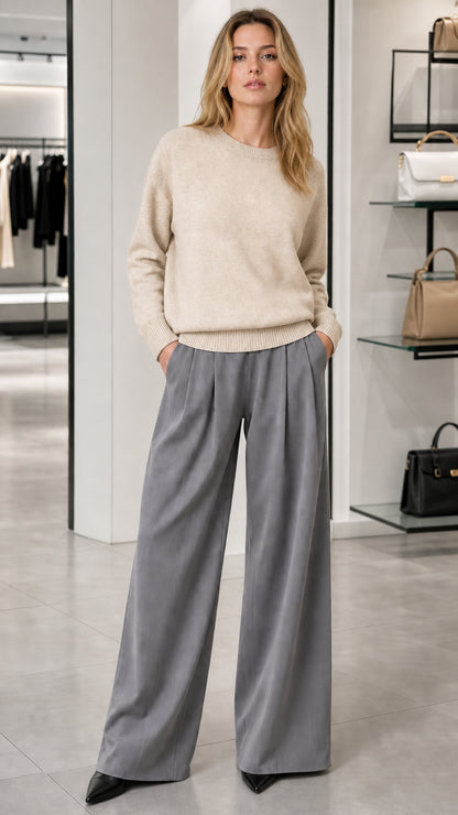 Model wearing cream oatmeal crewneck knit sweater with grey wide-leg trousers